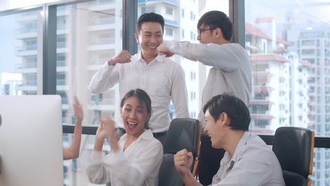 Millennial group of young businesspeople Asia businessman and businesswoman celebrate giving five after dealing feeling happy and signing contract or agreement at meeting room in small modern office.