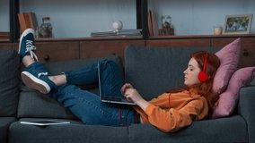 cheerful teenage girl lying and chatting on laptop