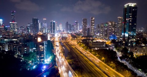 Night aerial hyperlapse of tel aviv skyline with urban skyscrapers, beautiful moving clouds, and cars on highway Israel
