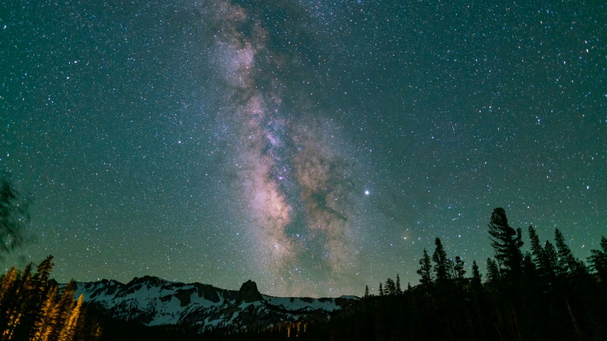 Astro timelapse tracking shot of Milky Way galaxy over alpine trees at Mammoth Lakes in Sierra Nevada Mountains, California 