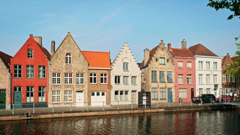 BRUGGE, BELGIUM - MAY 28, 2018: View of the historical houses in Bruges Brugge canal and a person running along the road. Bruges, Belgium