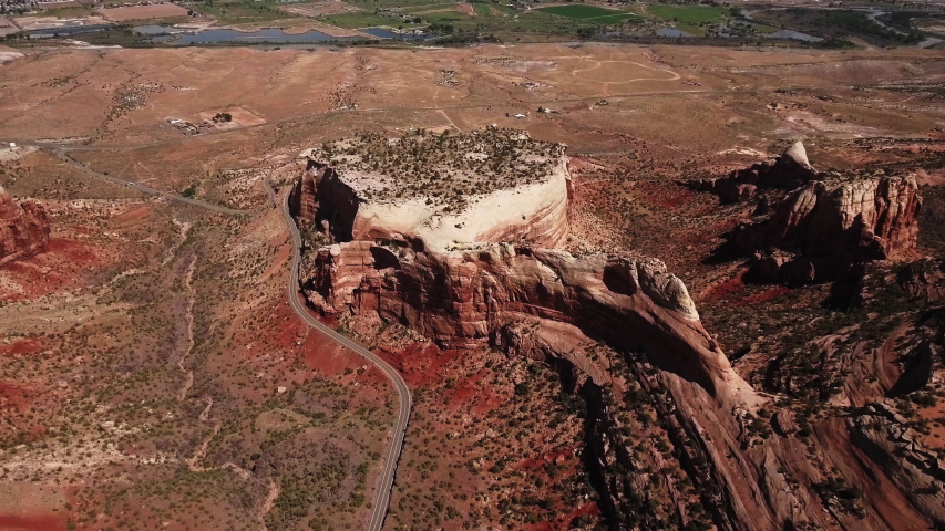 Aerial shot of red sunny plateau on Colorado National Monument with panorama of Grand Junction and Colorado River, USA