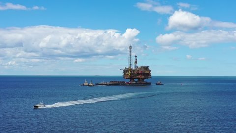 MIDDLESBOROUGH, ENGLAND - JUNE 20, 2019: The decommissioned North Sea oil platform 'Brent Bravo' is towed towards the mouth of the river Tees estuary where it will  be broken up. Aerial drone video.
