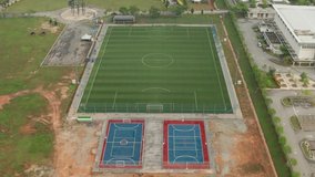 Aerial view of a football field in Cyberjaya City, Malaysia. Zoom out clip.