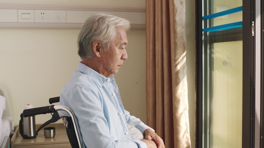 asian old man sitting in wheel chair alone in his room in nursing home