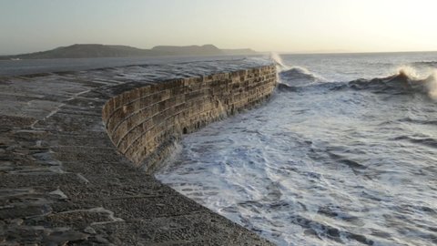 Big waves splashing on The Cobb in Lyme Regis, Dorset caused by gusty winds during high tide