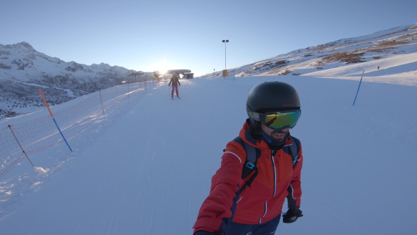 Happy couple having fun with ski on the snow in the mountains. Young man and woman going downhill with ski and having fun on the slope in the Alps, Italy. Winter sport and activities