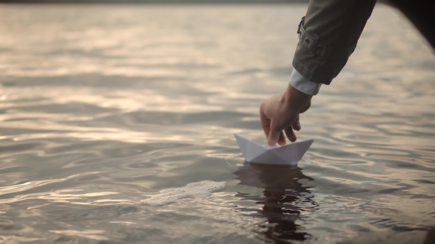 Paper Boat On River At Sunset. Man Hand Launch Paper Boat On Water And Pushing It Away. Origami Ship Sailing On Pond. Handsome Man Launching Origami Ship In Water On Sunset. Relaxing And Enjoying Time | Shutterstock HD Video #1042820752