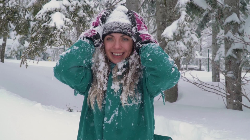 Ski resort entertainments. Happy young woman playing with snow