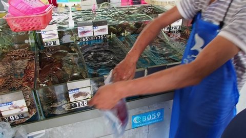 HAINAN, CHINA - 3 MAR 2019 – A fishmonger bags a live fish for a customer at a seafood wholesale and retail centre in China