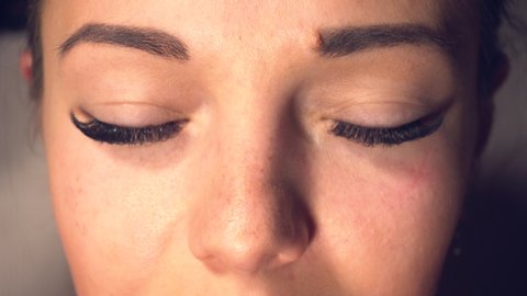 Woman with long eyelashes open her eyes and looking in camera