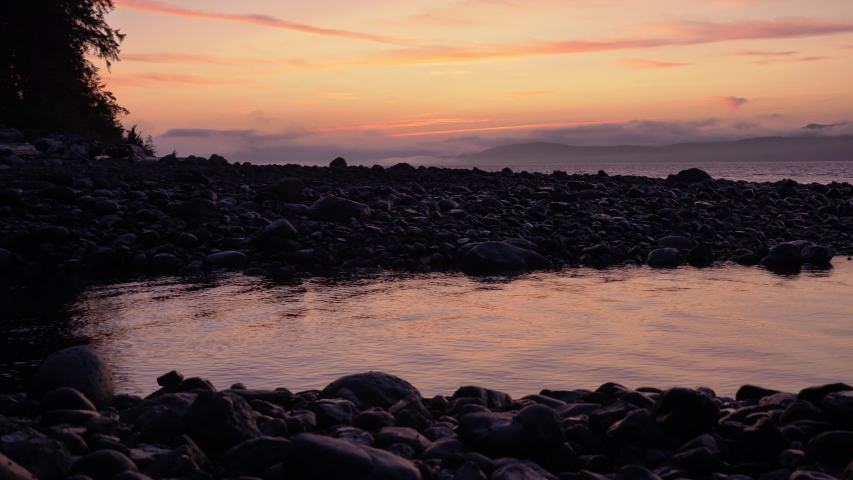 Wide, slow motion, sunset on a rocky beach, Vancouver Island, British Columbia Royalty-Free Stock Footage #1042829554