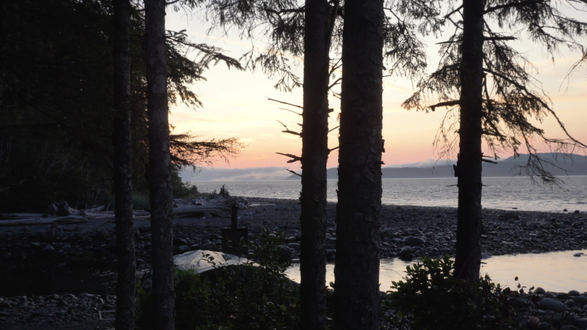 Wide, slow motion, sunset on a rocky beach with trees in foreground, Vancouver Island Royalty-Free Stock Footage #1042829563