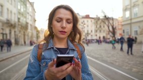 Young woman walking down an old street using smartphone and very emotionally reacts to what she sees there - Powered by Shutterstock - Get 15% off with code: PIKWIZARD15