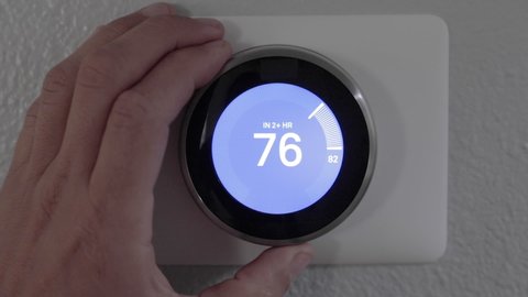 Honolulu, HI - December 6th, 2019: Man Adjusting Smart Thermostat Gadget At Home