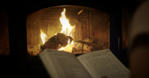SLOW MOTION, Woman Reading a Book by the Fireplace. Relaxed holiday evening concept. blurred book Close up