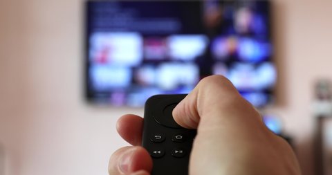 Man Watching Smart TV And Using Modern Black Remote Controller, Blurred TV In The Background - DCi 4K Video