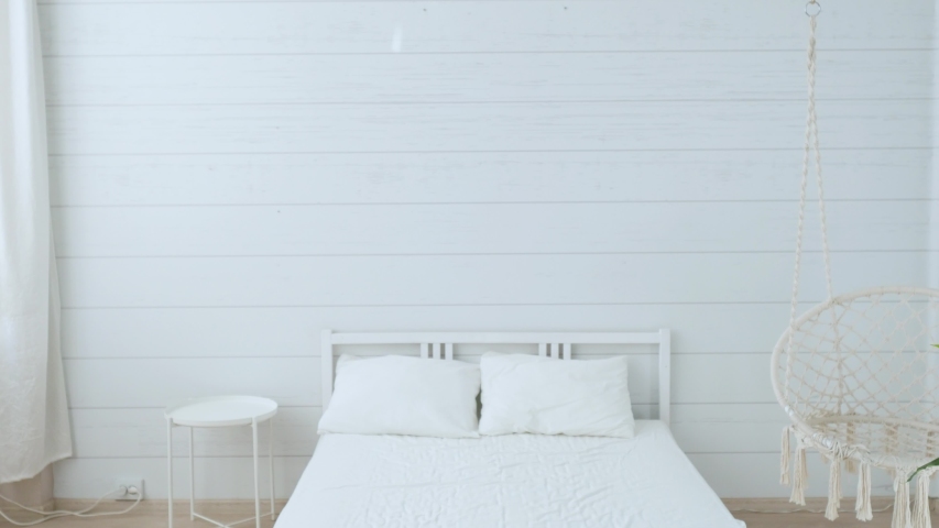 blonde woman makes the bed in a bright white room
