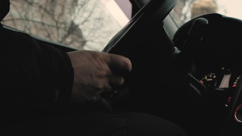 Male driver's hands hold the steering wheel, driving a car in the evening dark frame