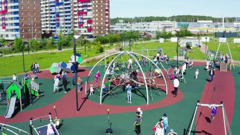 children and parents play on modern interesting safe playground in park near new apartment buildings aerial view