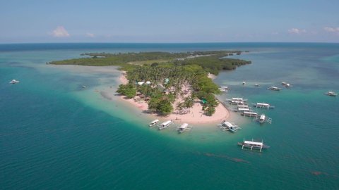 Tropical Honda Bay with clear waters, Cowrie Island packed with boats, drone shot in Palawan, Philippines