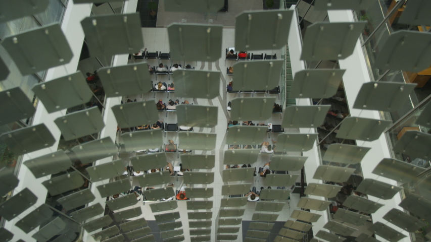 Closeup view of glass elevator with square ornaments moving fast down mall hall with conference
