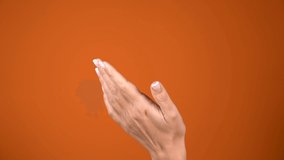 Closeup view of white adult woman clapping hands isolated at bright orange background. Real time 4k video footage.