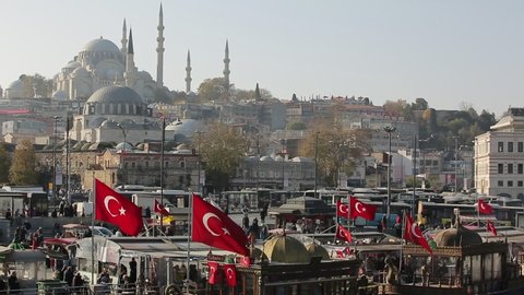 Istanbul, Turkey - Dec.10, 2019: Footage of waving Turkish flags and the famous Suleymaniye Mosque ahead in Istanbul city.View from Galata Bridge.