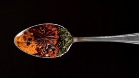 A Full Spoon Of exotic spice falling down  on black background closeup in super slow motion