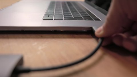 Plugging in usb-c hub into a laptop on wooden desk medium shot