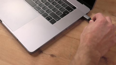 Plugging in usb-c hub into a laptop on wooden desk
