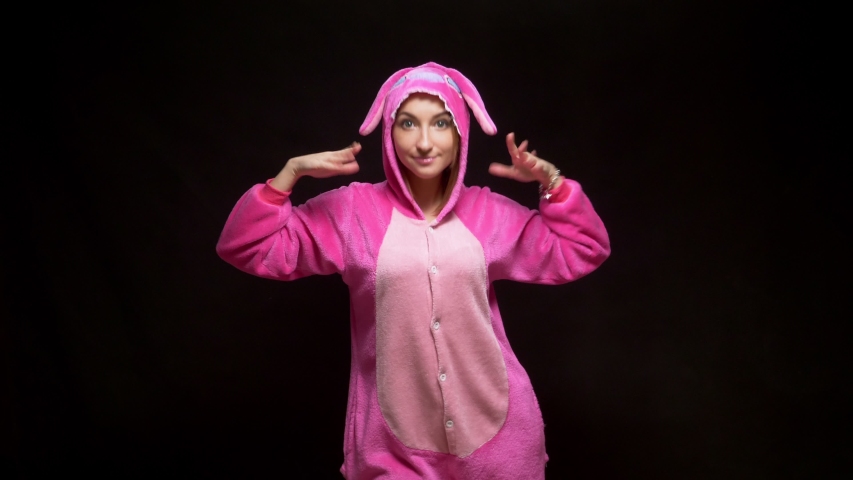 funny girl in jumpsuit kigurumi dances on a black background.