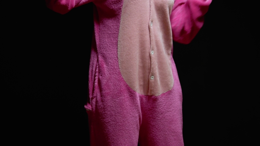 funny girl in jumpsuit kigurumi dances on a black background.