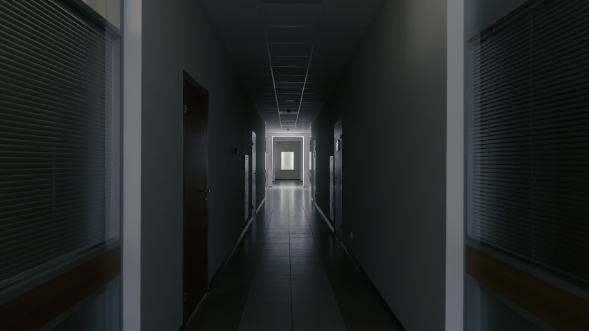 Tracking inside a long dark gloomy corridor of abandoned business center with offices or hospital at night. Concept of tunnel or horror. Leaved place Royalty-Free Stock Footage #1042931398