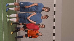 Vertical format video of two female soccer players standing in line while blocking free kick of opposing team. Girls in red uniform scoring a goal and celebrating victory during game on indoor field