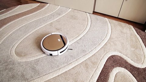 A black cat plays with a robotic vacuum cleaner that cleans the floor.pet playing with robot vacuum cleaner