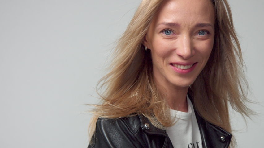 Closeup portrait slow motion from 60 fps woman with blonde hair blowing watching to the camera.Caucasian woman natural makeup watching to the camera