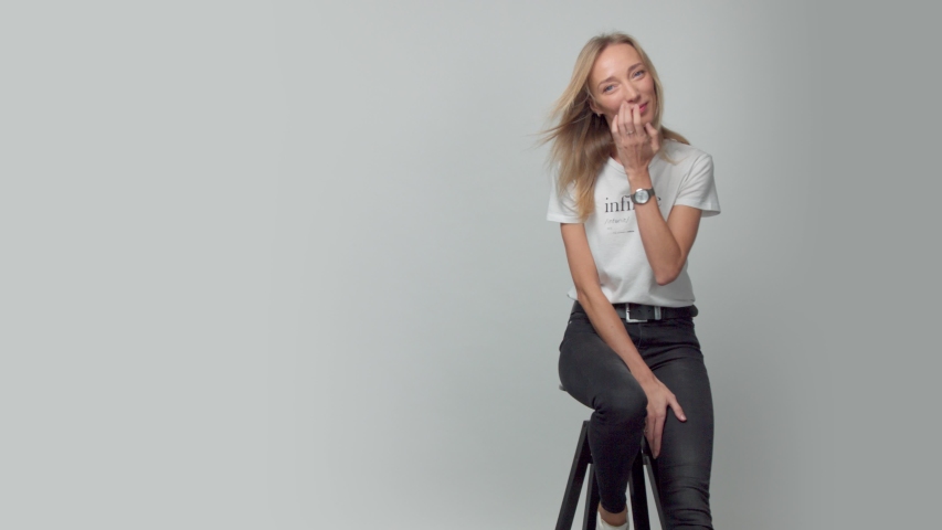 panned portrait of young blonde woman alone in studio wears a t-shirt with infinite text on it