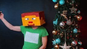 Masked man makes a selfie near the Christmas tree on smartphone records video, talks with subscribers. Modern and festive approach to social media sharing during the holiday season. Holiday Greetings 