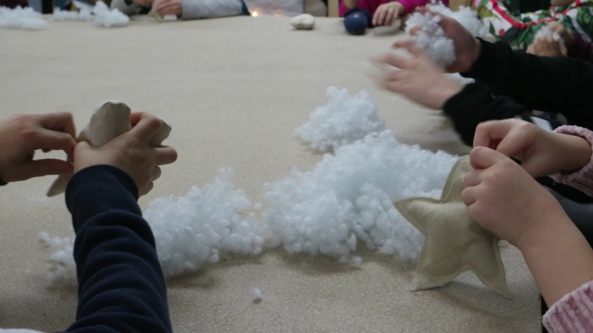 Children fill handmade textile Christmas decorations with white fluffy stuffing for soft toys
