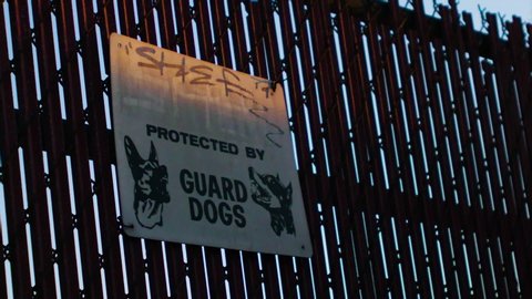 Long Beach, California / USA - August 14, 2019: Large sign outside fence in Port of Long Beach warns area guarded by attack Dogs