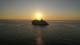 Aerial drone video of luxury yacht docked in Aegean deep blue sea at sunset with beautiful golden colours, Greece