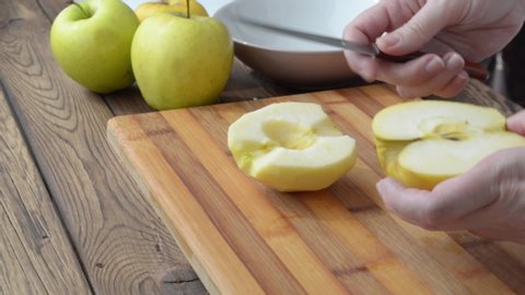 Female hands coring half of the fresh apple with fruit knife over the wood cutting board
