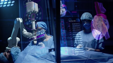 Team of Professional Surgeons perform a Delicate Operation using Medical Surgical Robot while observing Data on Transparent Screens. Modern medical equipment. Robotic arm for minimal invasive surgery.