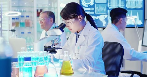 asian scientist team use microscope in the laboratory