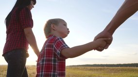 happy family little boy a holds parents hand walking go slow motion video concept. happy teamwork dad man mom girl and son boy child hold hands walk go on lifestyle field in nature .happy family