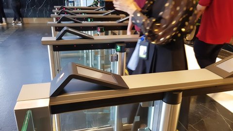 Turnstile gate inside office building with people use key card access walking in and out from the area. Smart building security process only authorize person can enter the area. 4K UHD