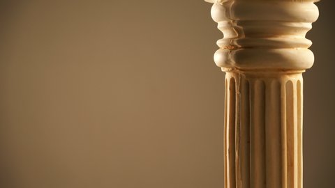 Single ancient corinthian column rotating slowly on grey background