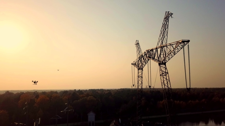 AERIAL: Drone inspection power line. Flying up the high voltage electricity tower and power lines at sunset above the beautiful forest and lake Royalty-Free Stock Footage #1042986670
