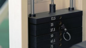 Close up on black metal weights with different numbers on them attached to counterbalance piston on gym machine